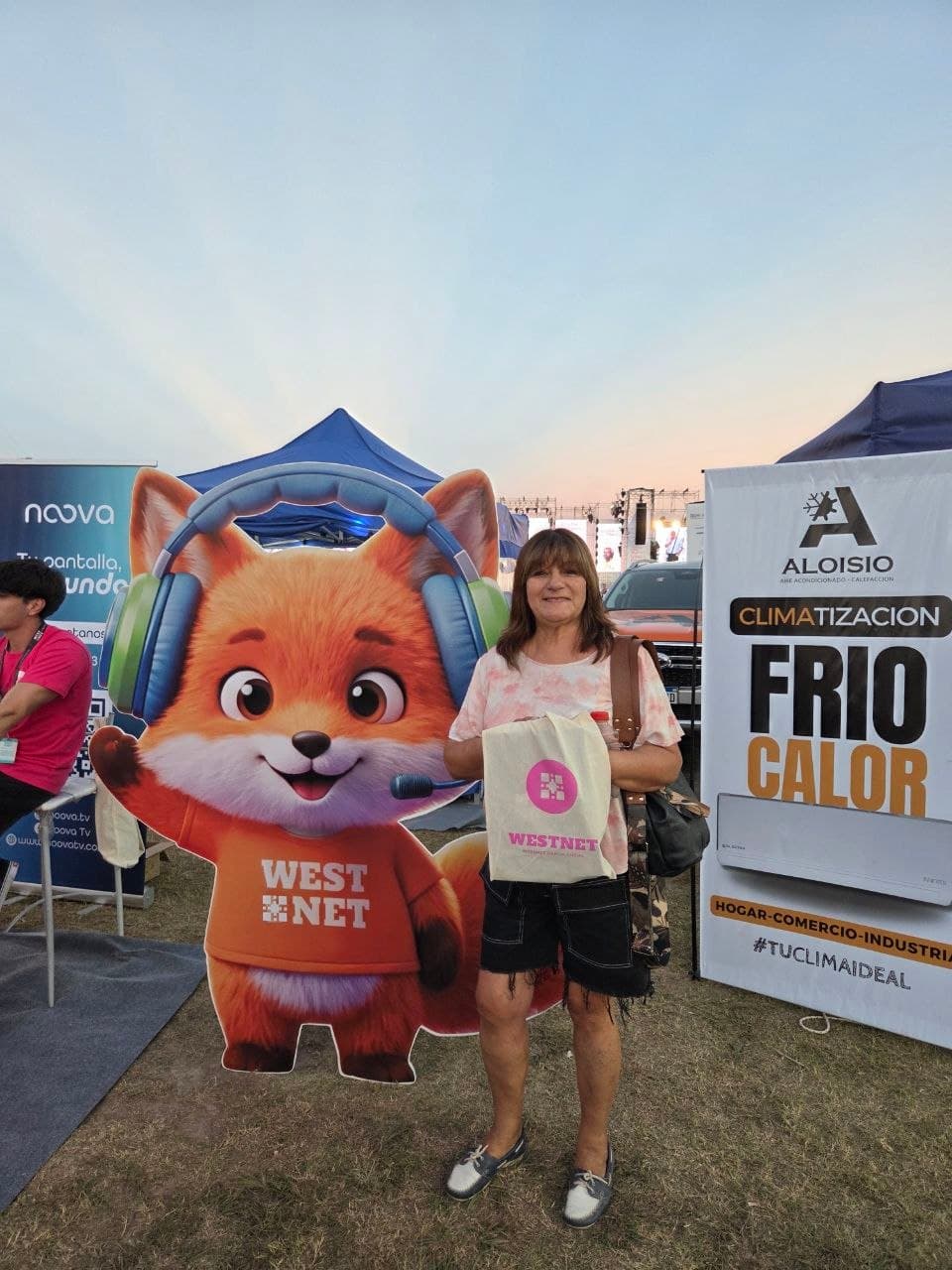 Visitante con un bolso de Westnet junto a la mascota zorro troquelada, al atardecer