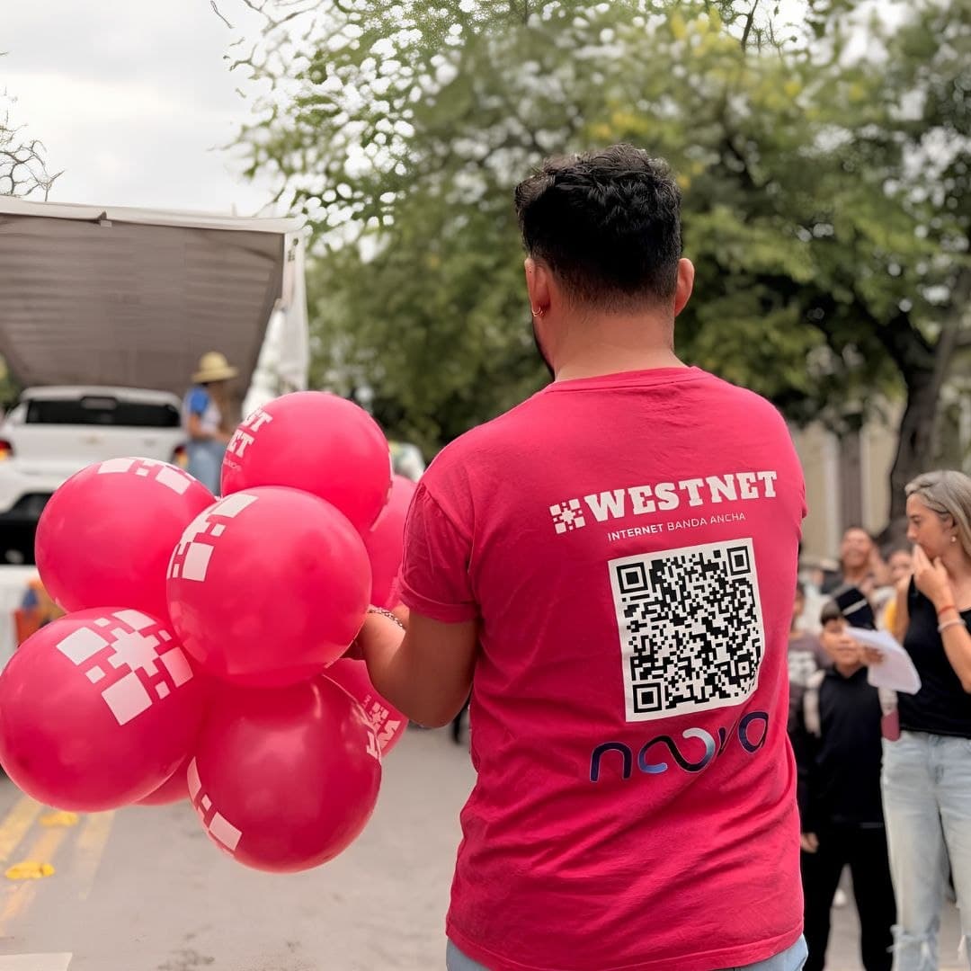 Integrante del equipo Westnet con globos de la marca en la calle, durante un evento de Vendimia