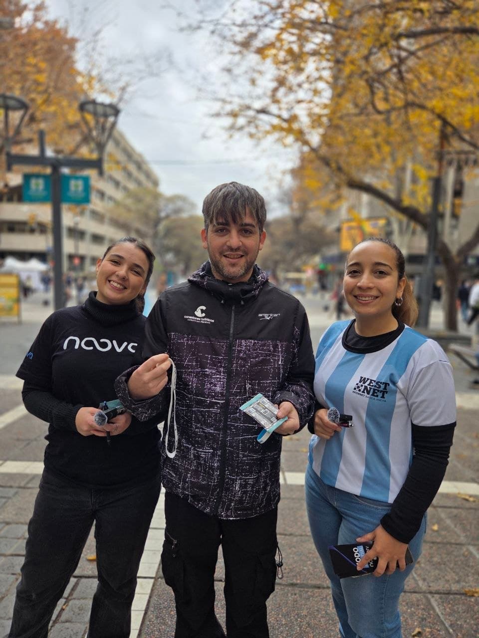Tres integrantes del equipo Westnet y Noova posando en una calle arbolada del centro de Mendoza